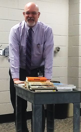 Professor pushing cart of books into a classroom. 